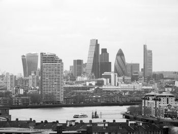 Modern buildings by river against sky in city