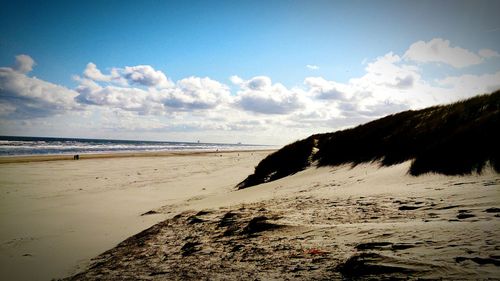 Scenic view of beach against cloudy sky