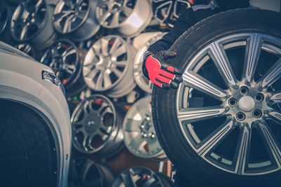 Midsection of manual worker holding tire at auto repair shop