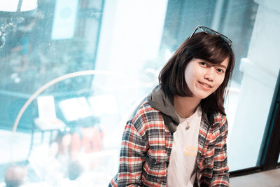 Portrait of smiling young woman against window