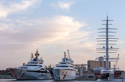 Sailboats moored at harbor against sky