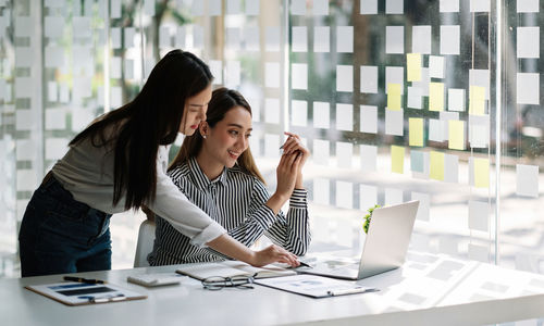 Business colleagues using laptop on desk at office