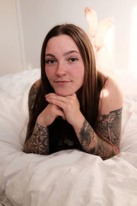 Portrait of young woman lying on bed at home