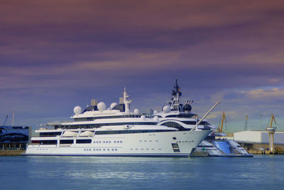 Boats moored at harbor against sky during sunset