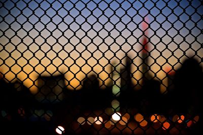 Defocused image of silhouette chainlink fence against sky during sunset