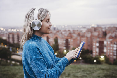 Woman listening to music and using smart phone at sunset
