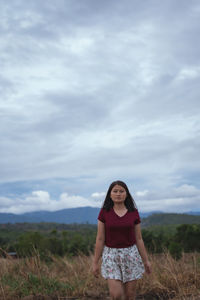 Portrait of woman standing on field against sky