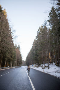 Rear view of a man walking on road