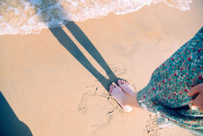 Low section of woman standing on sand at beach