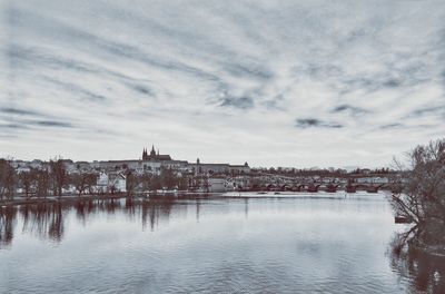 Buildings by river against sky in city