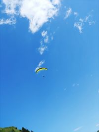 Low angle view of person paragliding against blue sky