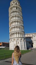 Rear view of woman against building against clear blue sky