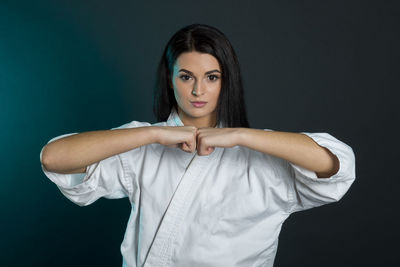 Portrait of karate woman standing against black background