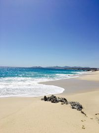 Scenic view of beach against clear blue sky