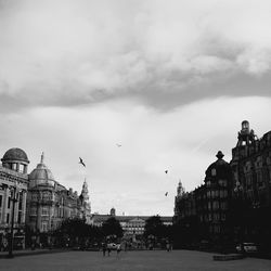 View of buildings in city against cloudy sky