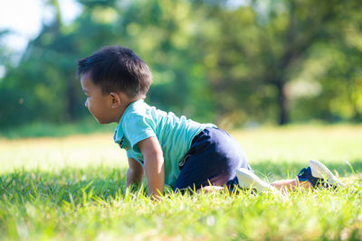 Side view of baby boy crawling on grassy land