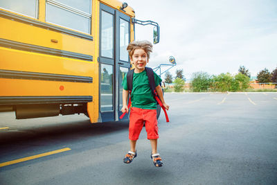 Full length portrait of smiling boy standing on bus