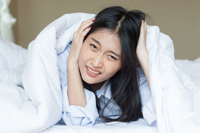 Portrait of young woman lying down on bed