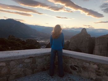 Rear view of woman standing on mountain against sky