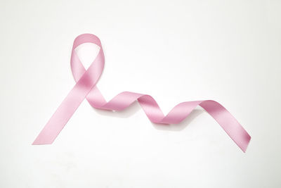 Close-up of pink ribbon on white background