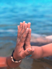 Close-up of couple hands over sea