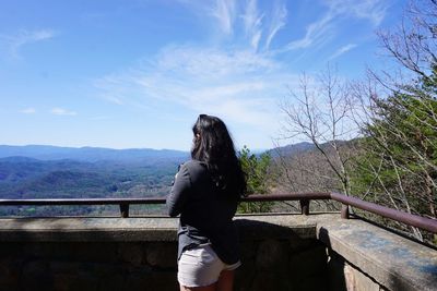 Full length of woman standing on railing against sky