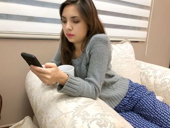 Young woman using phone while sitting on table