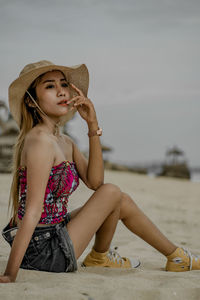 Full length of a girl sitting at beach against sky
