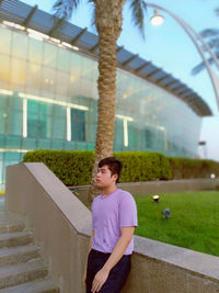 Portrait of young woman standing against building
