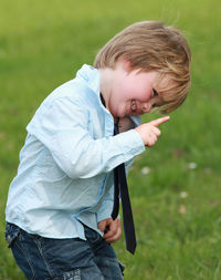 Close-up of cheerful boy gesturing while standing on grassy field