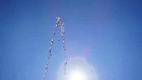 Low angle view of water splashing against blue sky