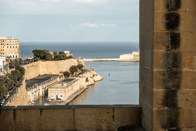 Buildings by sea against sky