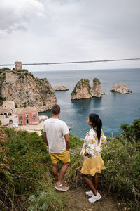 Rear view of people looking at sea against sky