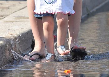 Low section of mother and daughter walking in water