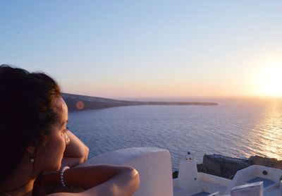 Woman looking at sea against sky during sunset