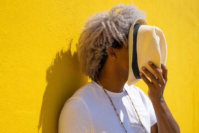 Portrait of senior man standing against yellow wall