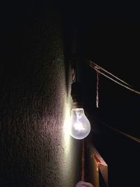 Illuminated light bulb hanging at night