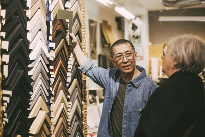 Craftsman showing frames to female customer at workshop