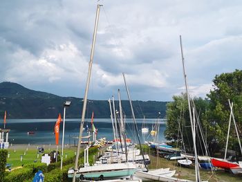 Sailboats moored at harbor against sky