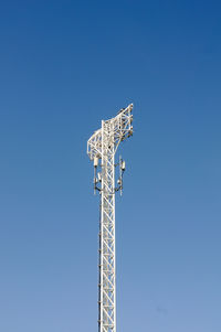 Low angle view of communications tower against clear blue sky