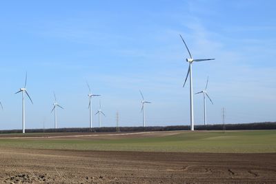 Windmills on field against sky