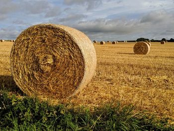 Hay bales on field against sky