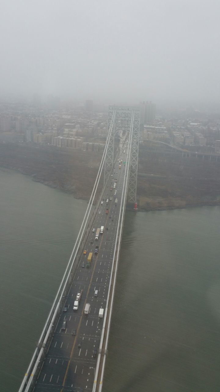 water, city, architecture, built structure, cityscape, river, building exterior, high angle view, fog, transportation, sea, foggy, copy space, bridge - man made structure, aerial view, sky, skyscraper, connection, day