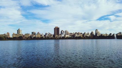 City at waterfront against cloudy sky