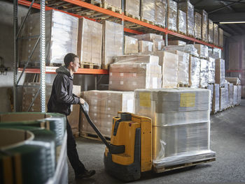 Man operating pallet jack in storehouse