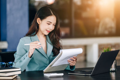 Young woman using mobile phone while sitting on table