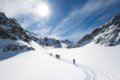 People walking on snowcapped mountain against sky