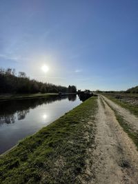 Canal amidst field against sky