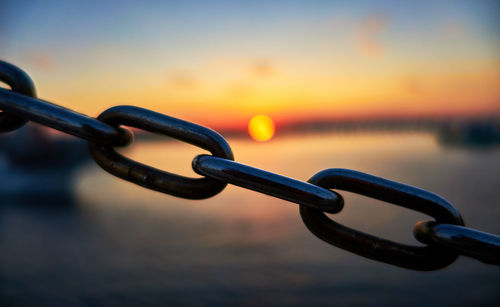 Close-up of chain against sea during sunset