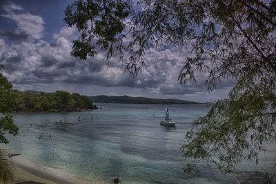 Boats in sea against cloudy sky